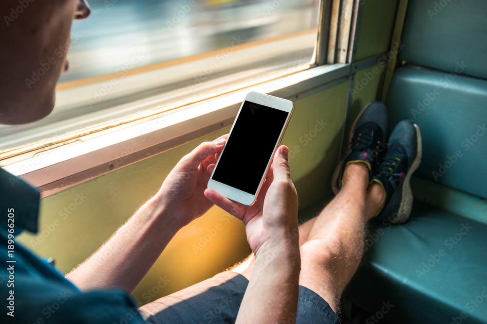 Man sitting in a train in motion holding a phone in his hands Man sitting in a train in motion holding a phone in his hands