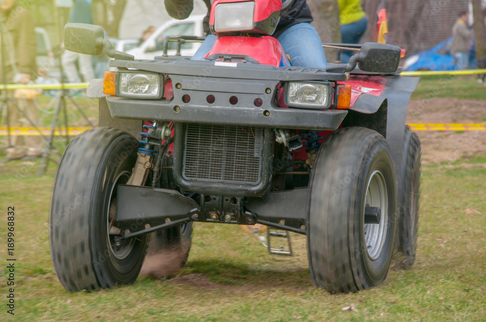 Obraz premium Mensch fährt ein Quad dynamisch in voller Fahrt auf Grasfläche im Sonnenschein