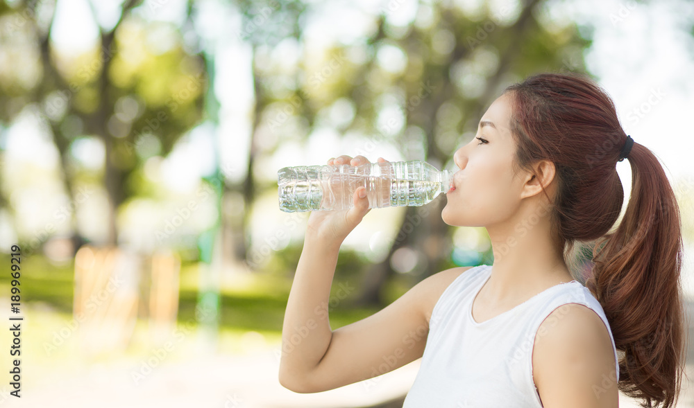 Young beautiful woman drinking water at summer green park. Young beautiful woman drinking water at summer green park.