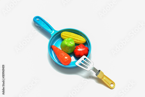 Children's plastic frying pan with vegetables on a white background