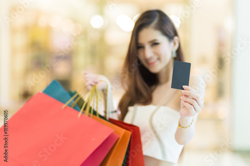 Beautiful woman holding shopping bags and credit with smile and happy in the shopping malls , consumerism or payment concept.