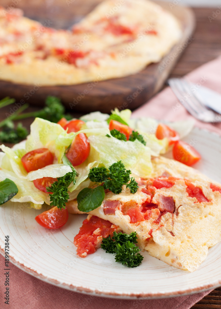 Homemade spicy Omelette with ham, tomatoes, pepper, cheese and herbs