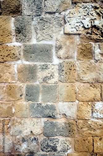 Old antique wall from demaged sandy brown stones front view vertical closeup photo