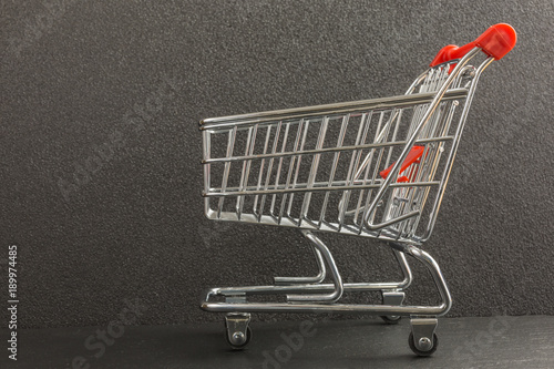 mini metal shopping trolley on black background - side view
