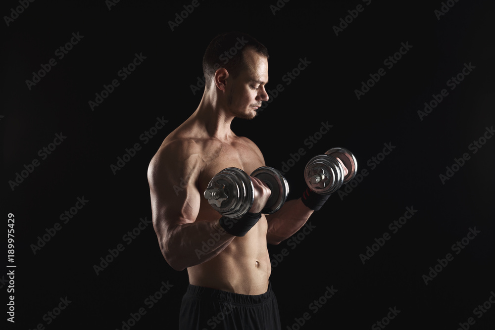 Strong athletic man with dumbbell showes naked muscular body