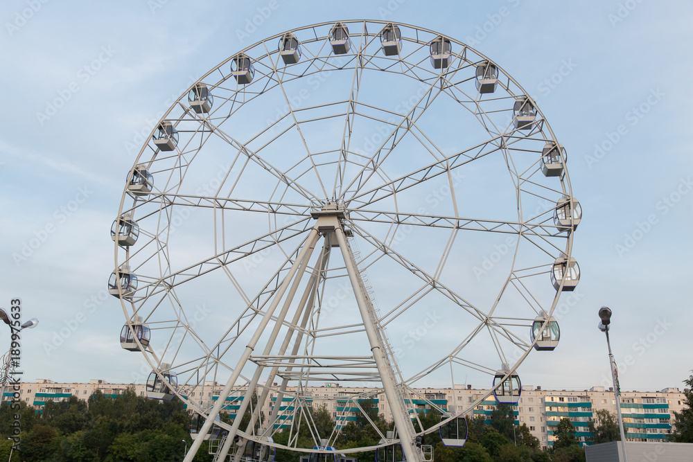 Ferris wheel on a summer day against a high-rise building