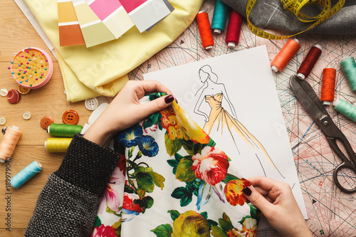 Female fashion designer working with fabric sample and drawn illustration