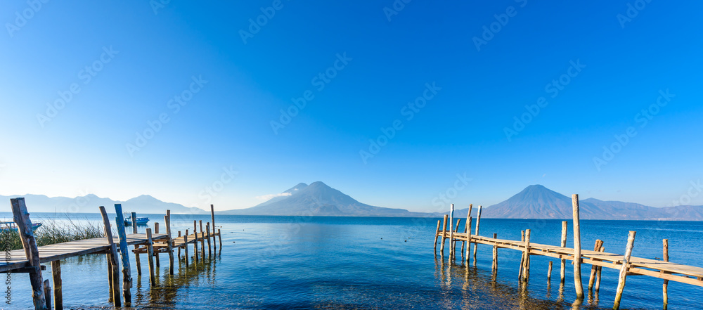 Naklejka premium Drewniany molo przy Jeziornym Atitlan na plaży w Panajachel, Gwatemala. W tle piękne krajobrazy wulkanów Toliman, Atitlan i San Pedro. Wulkan Highland w Ameryce Środkowej.