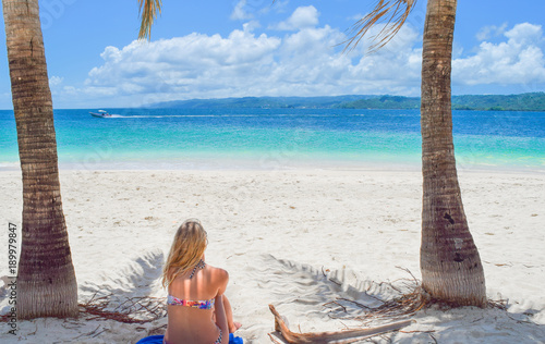 Frau sitzt im Bikini mit dem Rücken zur Kamera am weißen Sandstrand und schaut auf das Meer, Dominikanische Republik, Karibik, Samana photo