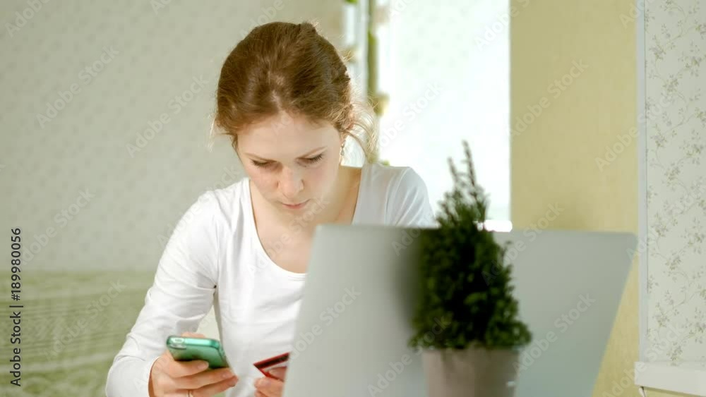 A young woman buys goods in an online store and pays a credit card through her phone A young woman buys goods in an online store and pays a credit card through her phone