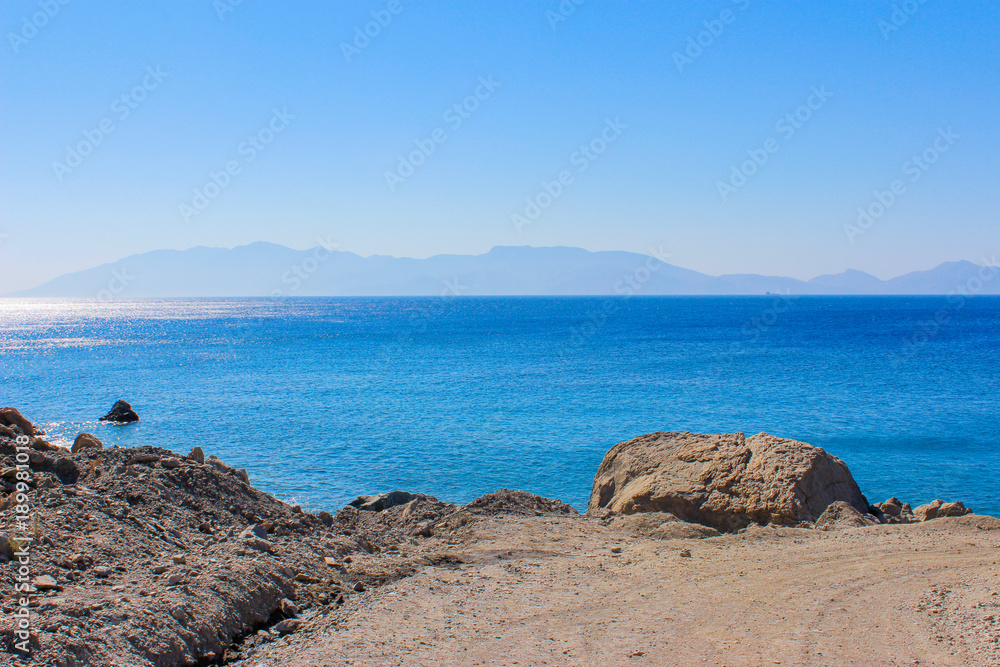 Wunderschöner Ausblick auf das blaue türkisfarbene Meer, an Felsen entlang Ausblick auf den Ozean, am Horizont sieht man eine Insel