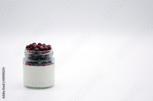 Fresh berries in the jar with the yogurt. On white background.
