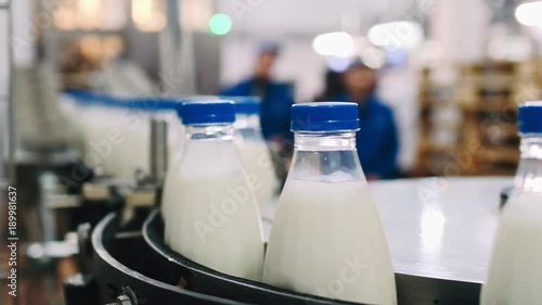 Conveyor line for pouring dairy products into plastic bottles at a milk factory in full-HD resolution in slowmotion. A lot of bottles go around the conveyor belt