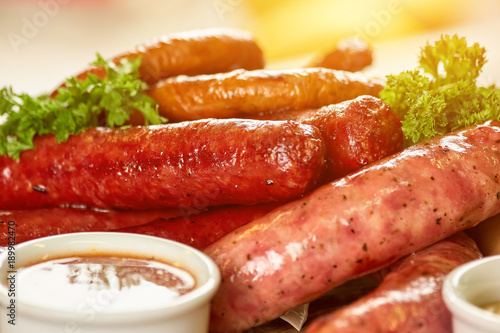 Different types of sausages closeup. Different types of juicy sausages and sauce in pot closeup.