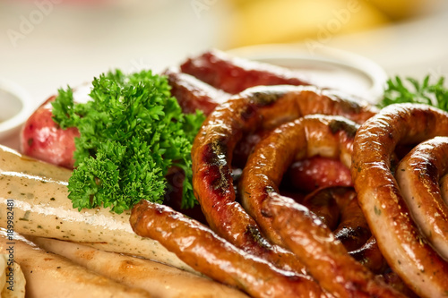 Curly and straight sausages with parsley. Closeup smoked sausages.