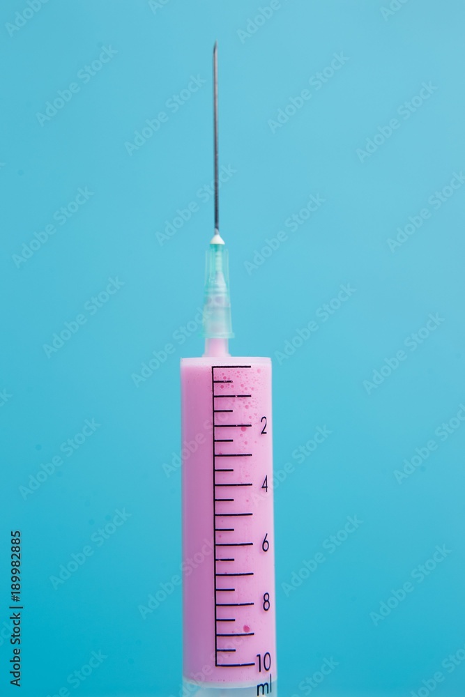 Close-up of medical syringe with pink medicine on blue background. Health care, medicine and pharmacy concept Close-up of medical syringe with pink medicine on blue background. Health care, medicine and pharmacy concept