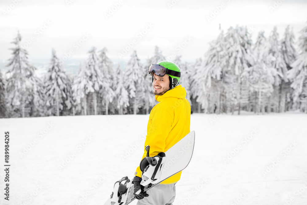 Man in winter sports clothes walking with snowboard at the snowy mountains