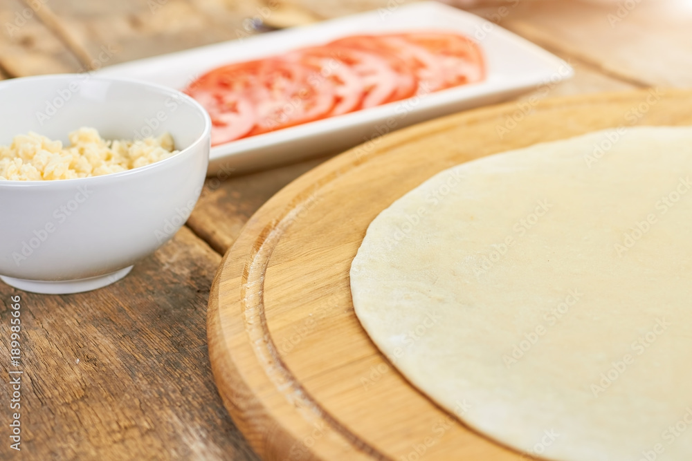 Pizza dough and side dish. Round dough sheet.