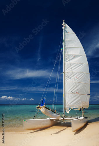 Sail boat, catamaran, on tropical beach with blue water