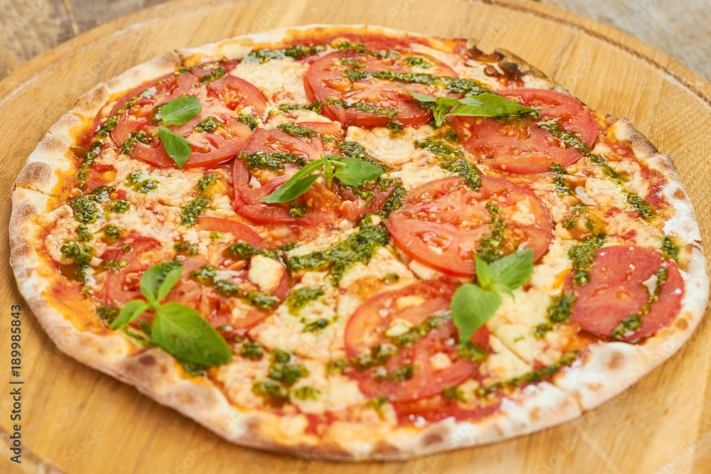 Top view tomato pizza with greens on wooden board. Appetizing cooked tomato pizza with basil. Top view tomato pizza with greens on wooden board. Appetizing cooked tomato pizza with basil.