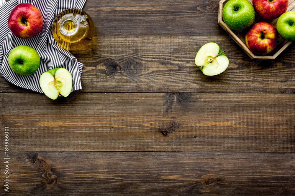 Light salad dressing. Apple cider vinegar in bottle among fresh apples on dark wooden background top view copy space Light salad dressing. Apple cider vinegar in bottle among fresh apples on dark wooden background top view copy space