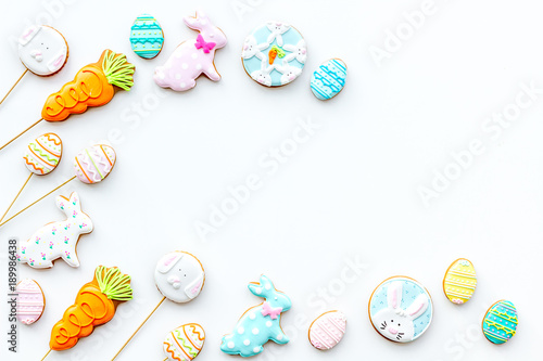 Sweets for celebrate Easter. Gingerbread in shape of easter bunny and easter eggs. White background top view copy space