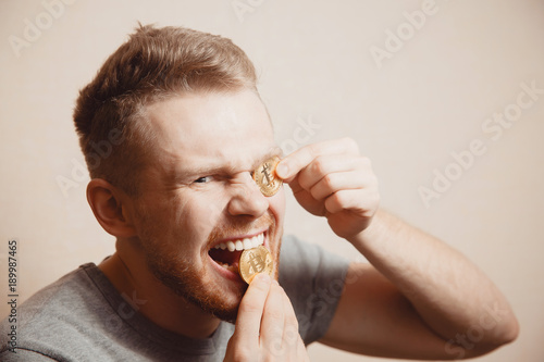 Bitcoin. Man bites a gold coin with his teeth © Parilov