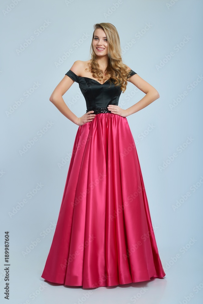 Wonderful girl wearing amazing long pink and black evening dress. Good choice for prom. Girl is very beatiful and has blonde curly hair, nice light make-up. She has pretty smile. Photo was taken on