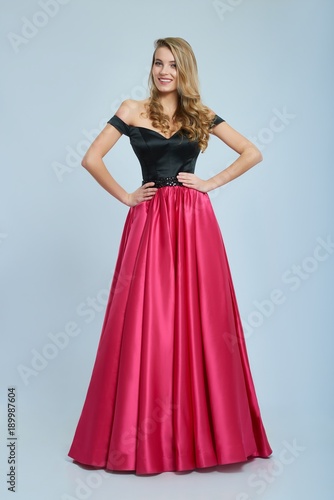 Wonderful girl wearing amazing long pink and black evening dress. Good choice for prom. Girl is very beatiful and has blonde curly hair, nice light make-up. She has pretty smile. Photo was taken on