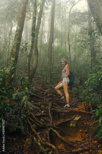 young woman trekking through dense lush green tropical Jungle photo