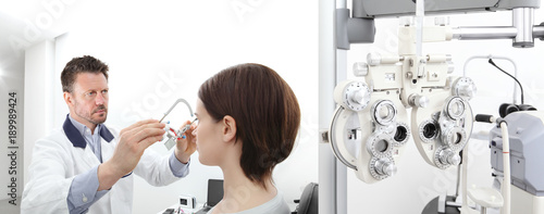 optometrist with trial frame examining eyesight woman patient in optician office