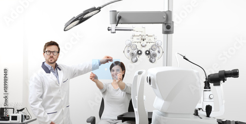 optometrist examining eyesight woman patient pointing at the hole on plexiglass in optician office, ocular dominance test