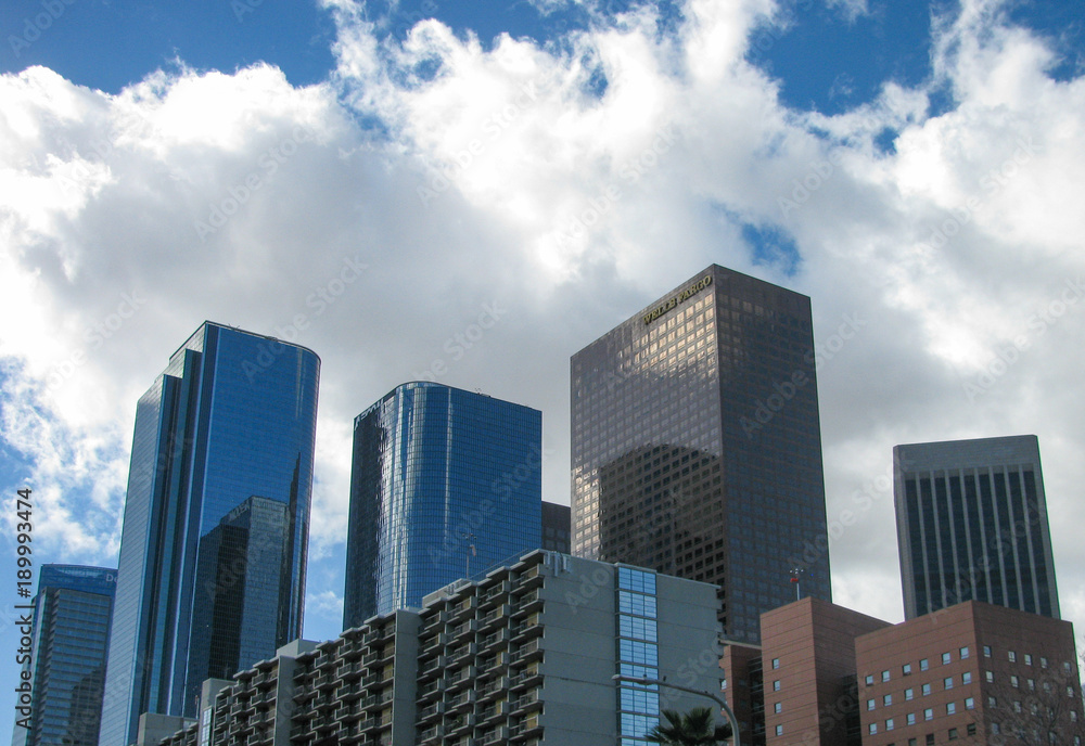 Buildings in the LA skyline on Bunker Hill in downtown Los Angeles viewed from below on Hill Street against a blue sky with white clouds