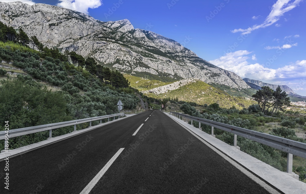 Fototapeta premium Country road through the rocky mountains and forest.