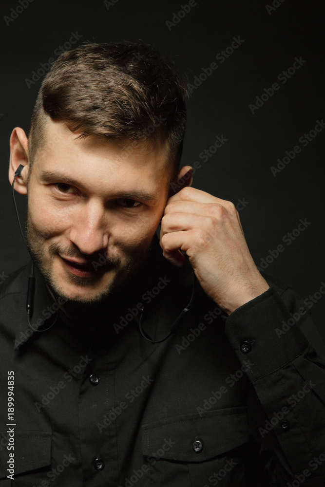 Man in headphones and black shirt on a black background