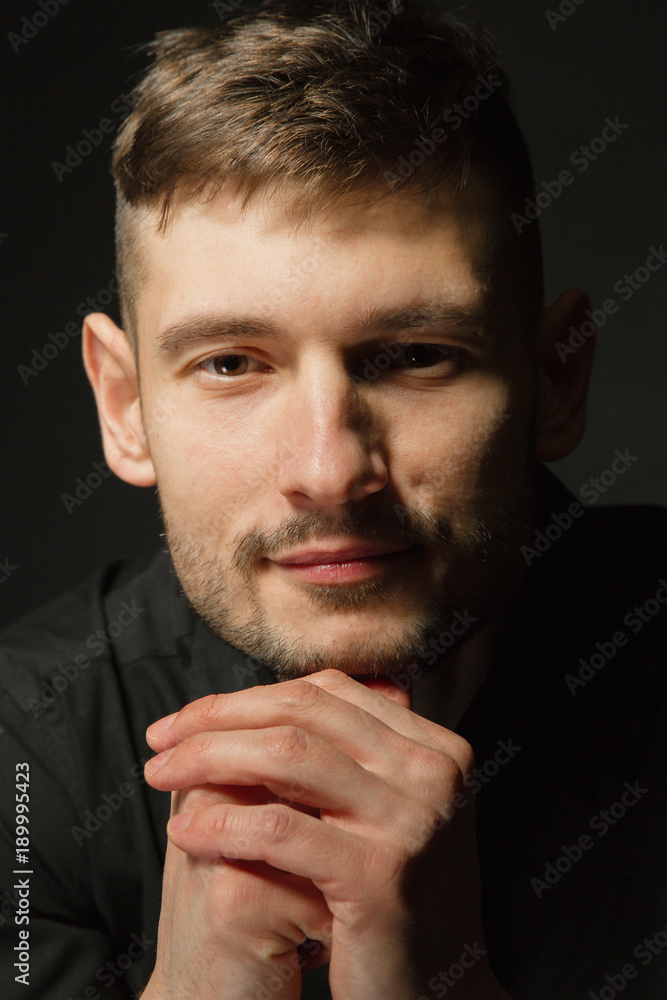 Handsome and positive guy in a black shirt on a black background Handsome and positive guy in a black shirt on a black background