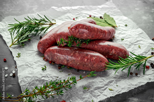 Foto Freshly made raw breed butchers sausages in skins with herbs on crumpled paper