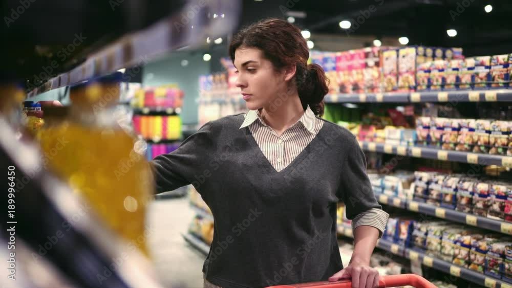 Young beautiful female costumer choosing oil in local grocery store. Young beautiful female costumer choosing oil in local grocery store.