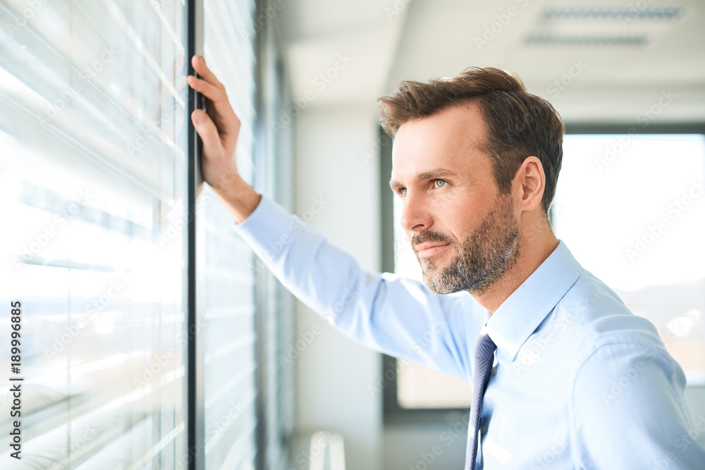businessman looking through the window at office businessman looking through the window at office