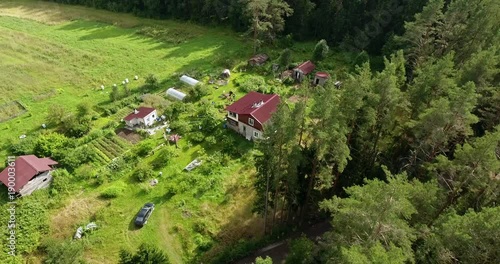 Flyover a farm with big field surround by the wood and lake