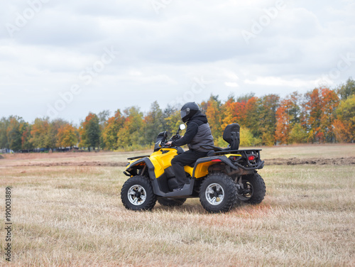 Driver in helmet on yellow quad bike on field