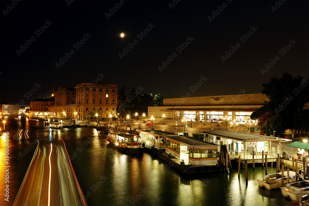 Water taxi’s and boats moving in the water way near the Venice Railway station at night