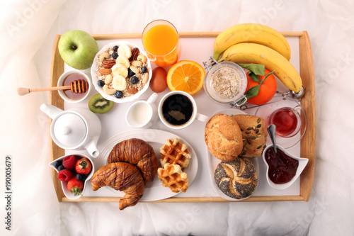 breakfast in bed with fruits and pastries on a tray -waffles  croissants  coffe and juice