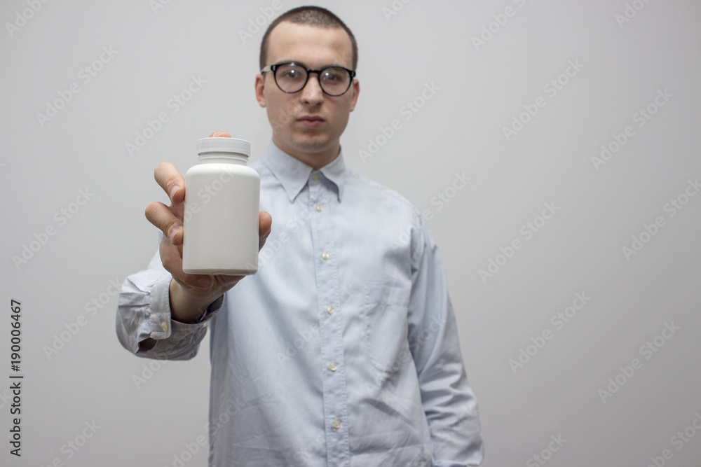 Young handsome doctor showing blank white bottle of pills medicaments. Healthcare and medicine concept. Selective focus and shallow DOF Young handsome doctor showing blank white bottle of pills medicaments. Healthcare and medicine concept. Selective focus and shallow DOF