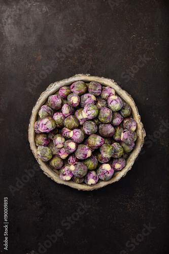 Purple Brussels sprouts in a bowl on dark background