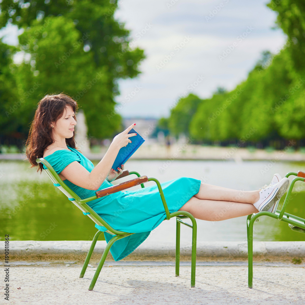 Fotografie Woman in green dress reading a book in Tuileries garden of Paris, France