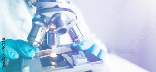 Close up of examining of test sample under the microscope in laboratory.