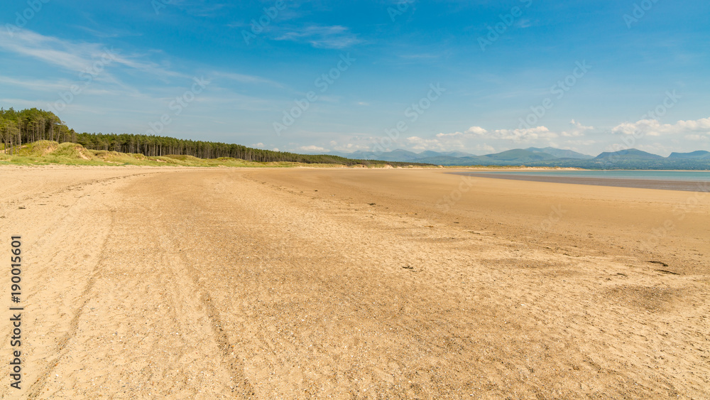 Llandwyn Bay in Anglesey, Gwynedd, Wales, UK - with Snowdonia mountain range in the background Llandwyn Bay in Anglesey, Gwynedd, Wales, UK - with Snowdonia mountain range in the background