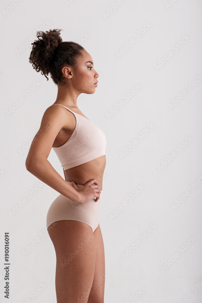 Side view profile of tranquil slim girl watching her weight. She is  demonstrating her slender figure. Copy space in right side. Isolated on  background Stock Photo