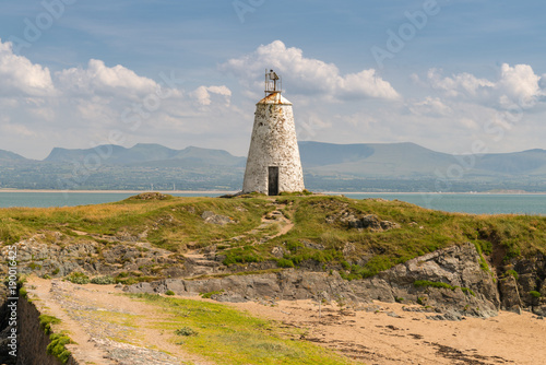 Twr Bach Lighthouse at Ynys Llanddwyn in Anglesey, Gwynedd, Wales, UK - with Snowdonia mountain range in the background